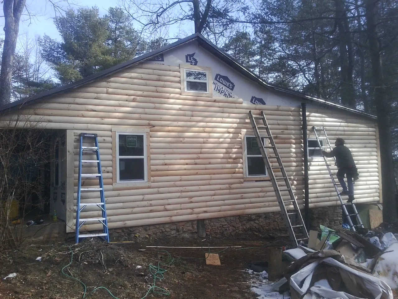 Ladders set against fresh log siding during an exterior remodel in Inman