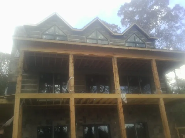 Dormers and porch framing on a large log home under construction — Roof Coating work by our crew in Inman