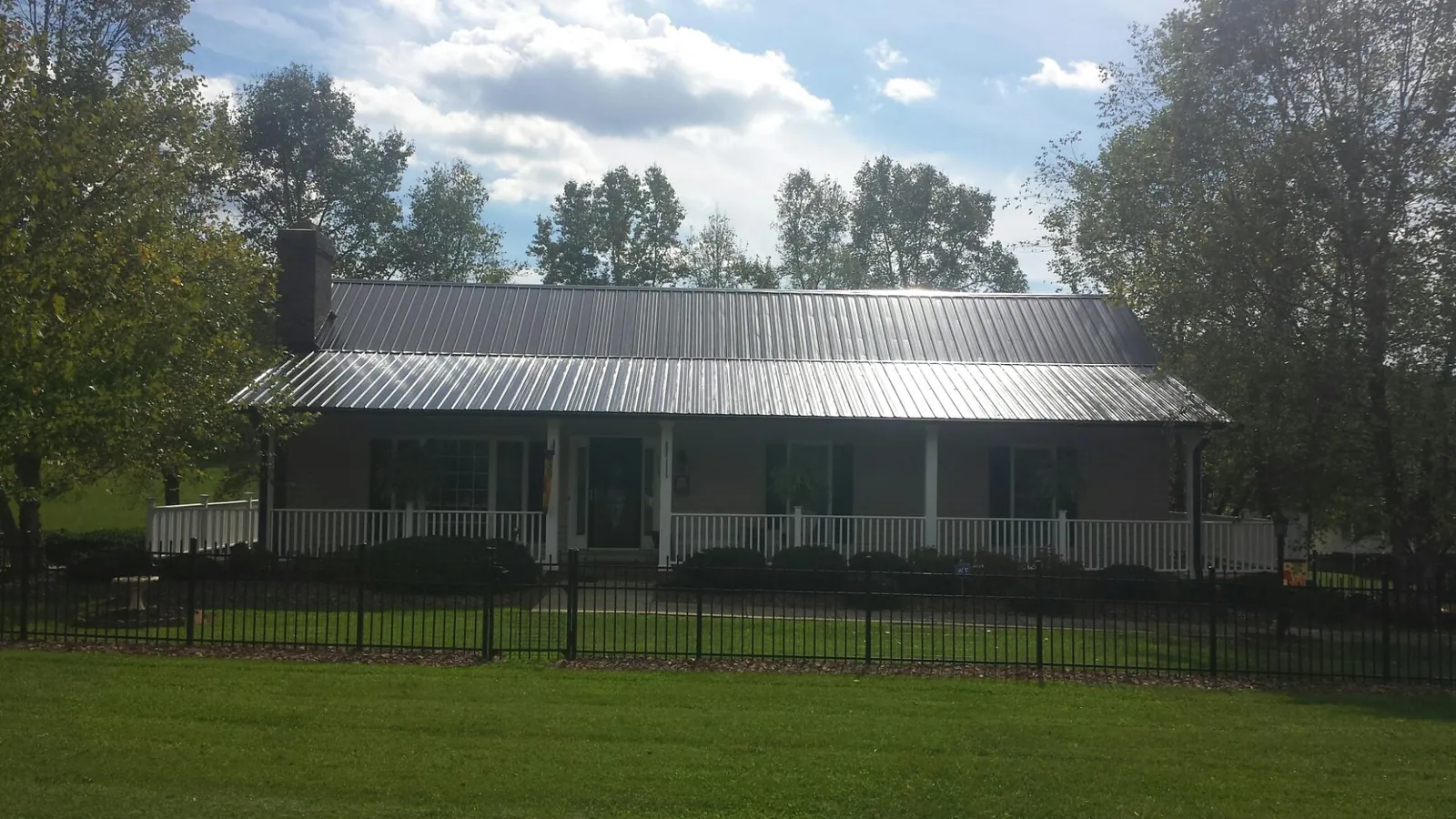 Gray metal roof on a brick ranch with a full width front porch — Gutter Guard Installation work by our crew in Inman